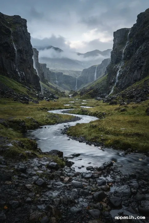 Low-angle portrait fine art landscape of the same misty basalt valley, with wet foreground stones, a silver winding river, dark volcanic cliffs, thin waterfalls, and drifting cloud.