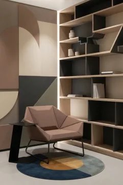 Graphic Geometric reading nook with sculptural rectangular shelving, a faceted lounge chair, patterned wall panels, and warm concealed lighting.