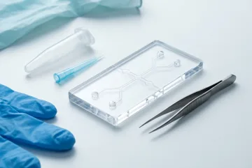 Transparent microfluidic diagnostic cartridge with sterile sampling tools arranged on a clean clinical laboratory surface in studio photography.