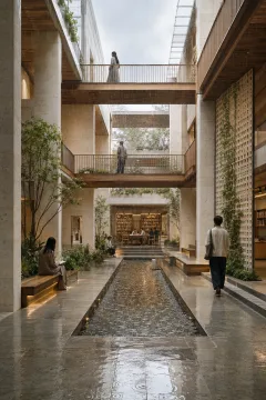 Portrait view of a contemporary rain-fed courtyard library with pale stone walls, timber bridges, ceramic screens, reflective water channels, greenery, and anonymous visitors during gentle rainfall.