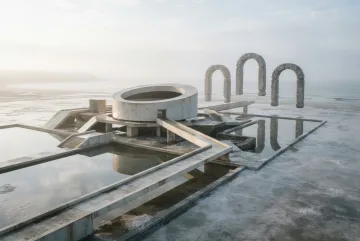 Surreal tidal observatory of pale concrete beneath three floating stone arches above reflective coastal pools.